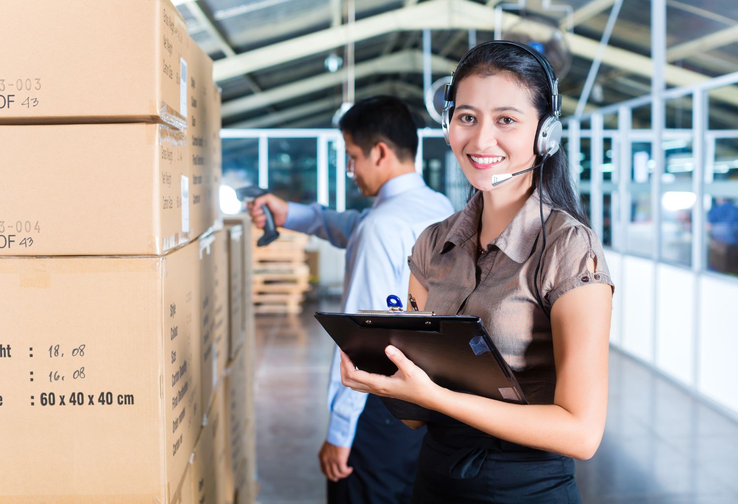 Young women in a suit with a headset in a warehouse representing Collection Services in Logistics Supply Chain Management.