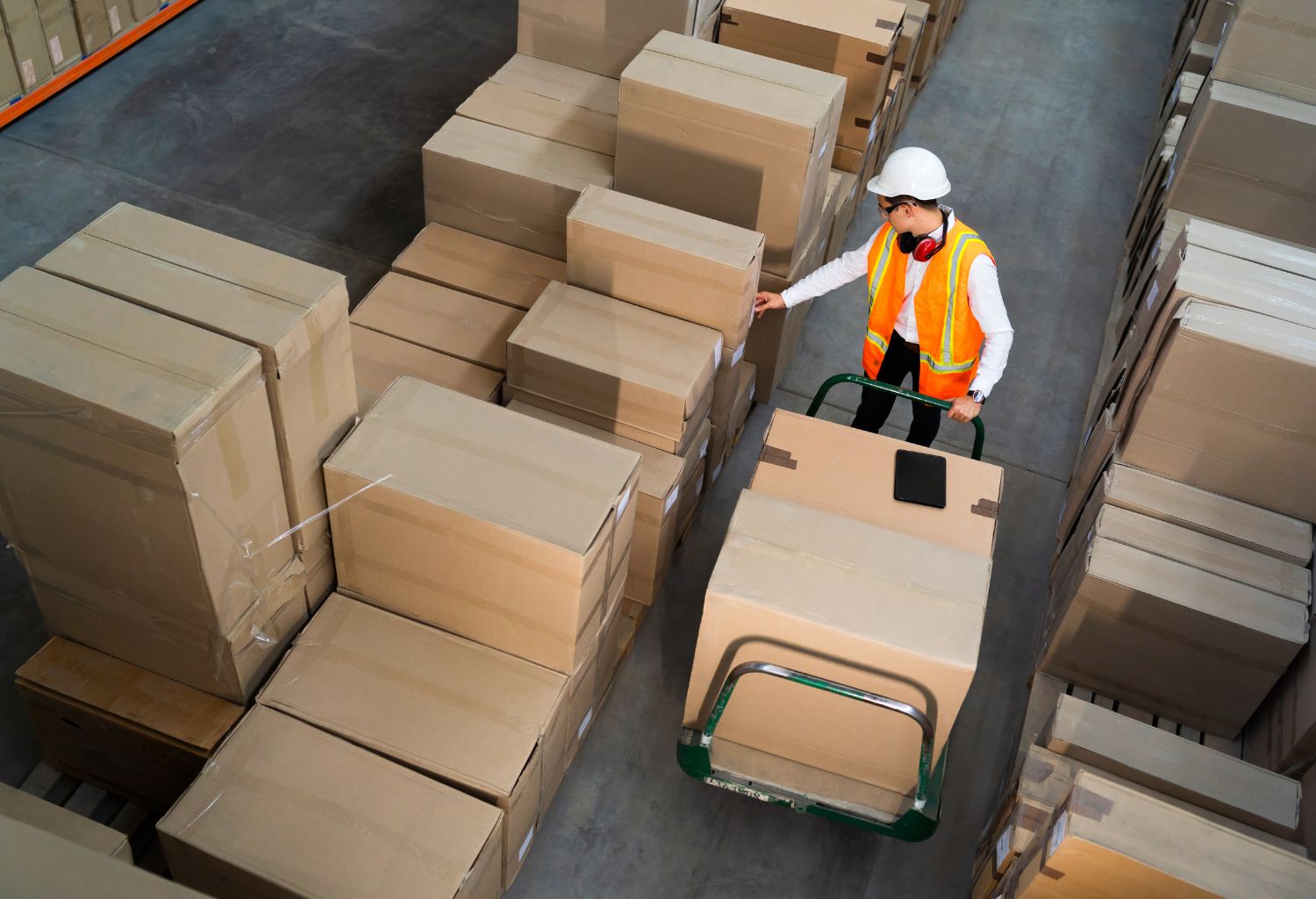 Reverse Logistics : Logistic warehouse worker delivering boxes on a trolley.